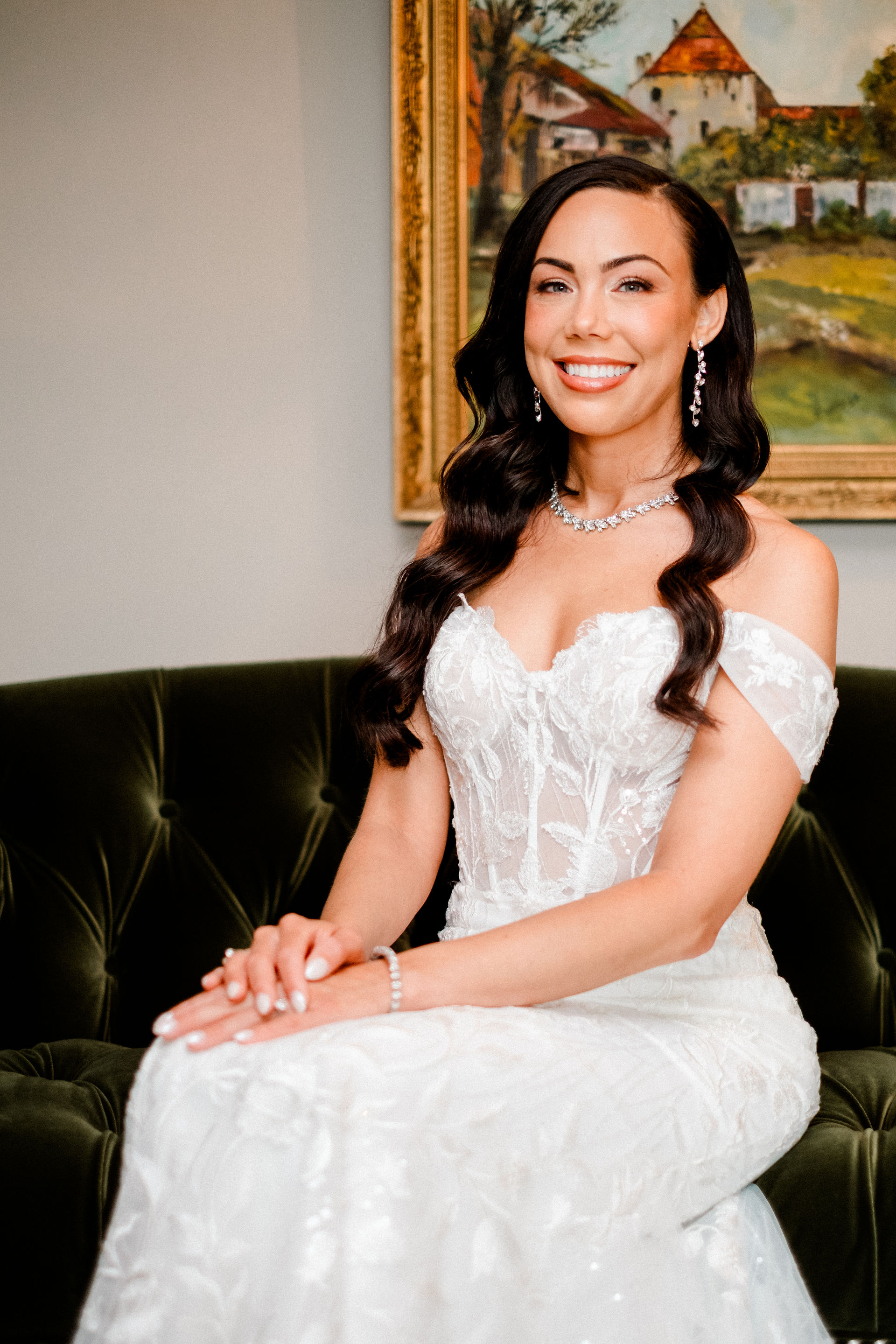 Bride posing and smiling sitting on a green velvet couch