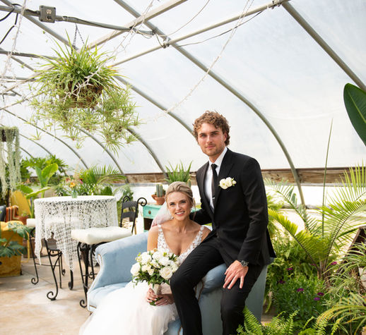 Couple picture in the tropical greenhouse sitting on a velvet blue couch