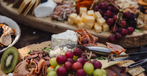 Close up shot of a cutting board with variety of cheeses, crackers and deli meats
