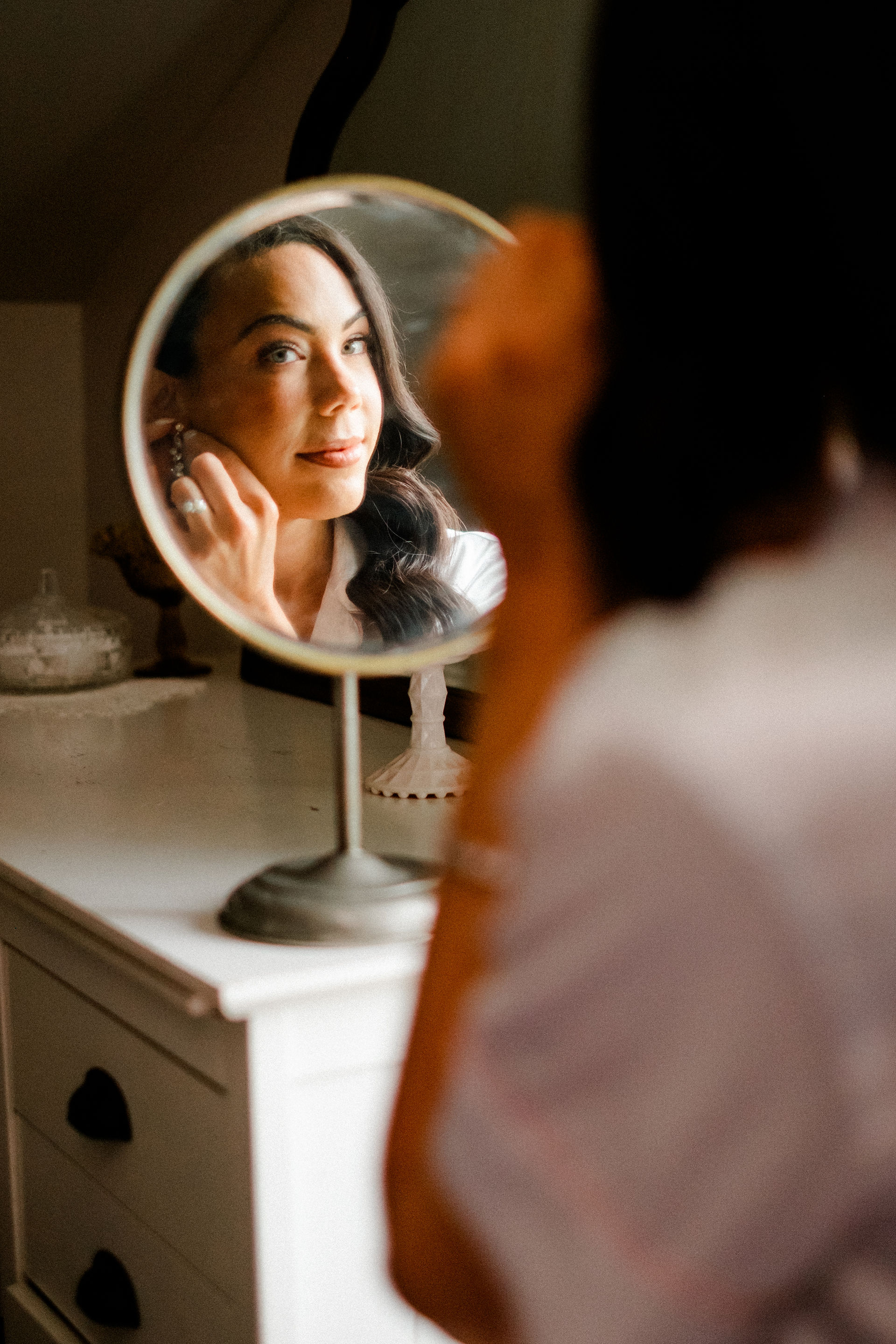 Bride putting on earrings looking into the mirror