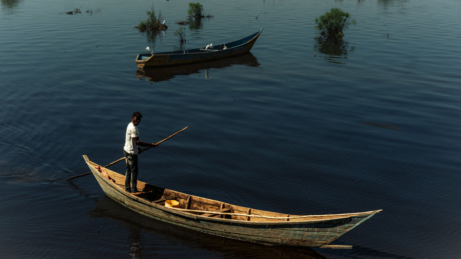 A man rows a boat while standing