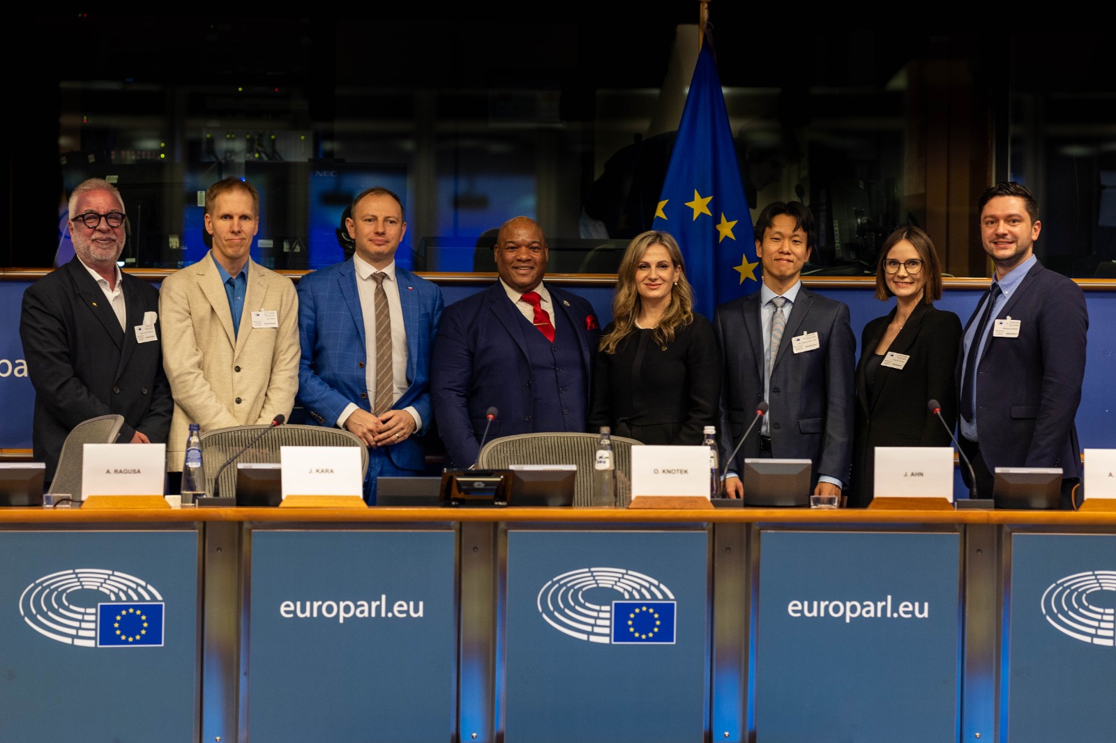 Eight far-right politicians, pastors, and "cult" leaders in suits pose in the European Parliament