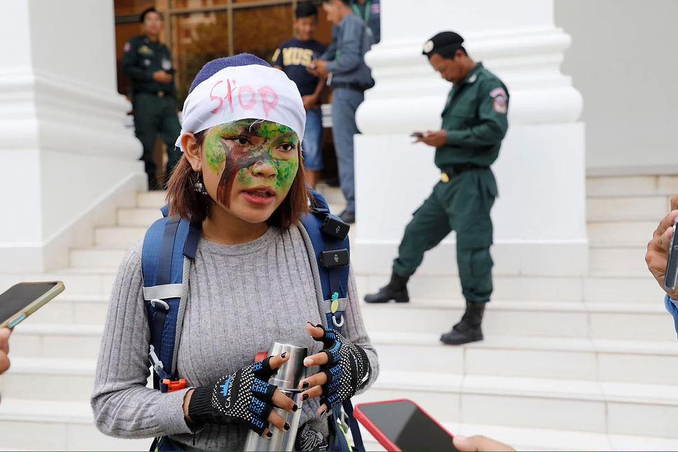 Lisa with her face painted and marked “STOP,” speaks to the media outside a guarded building.