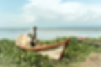 A tired-looking fisherman, his head wrapped in a shawl holds fishing nets in his hands.