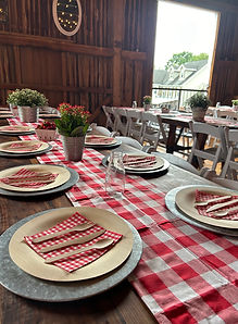 Rustic bridal shower table setup with floral centerpieces inside the historic timber-frame barn at Barn Swallow Farm in North