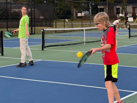 Two boys playing pickleball on an outside court