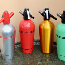Four siphons against a pink background, with silver and red, red and black, gold and mint green colours
