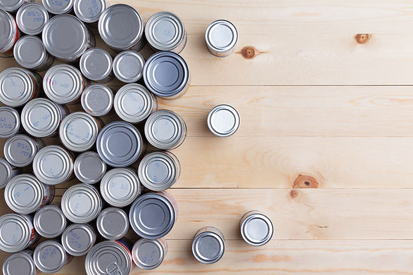 Multiple canned goods organized on a wooden surface.