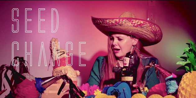 Sana and her piñatas standing against a pink background.