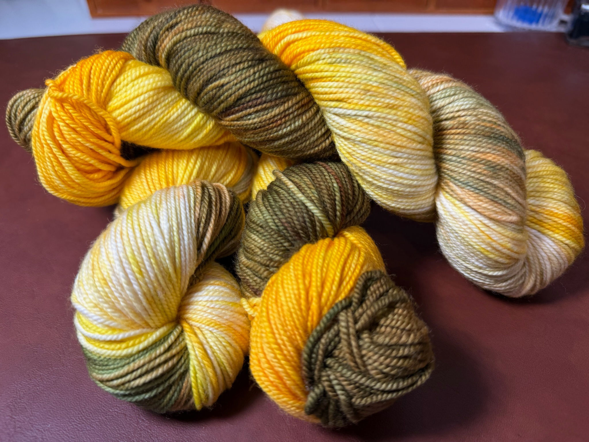 3 skeins Sunflower hand-dyed yarn. A blend of yellows, golds, and earthy greens inspired by fields of blooming sunflowers.
