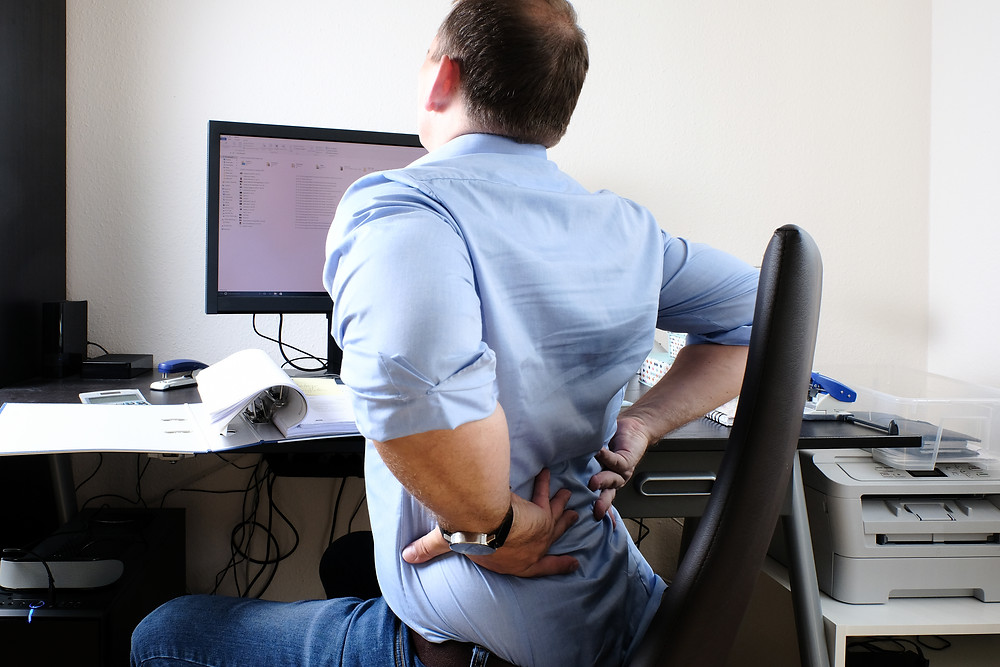 Rückenschmerzen durch zu vieles Sitzen im Büro