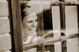 A smiling Bride at a window of one of the rooms.