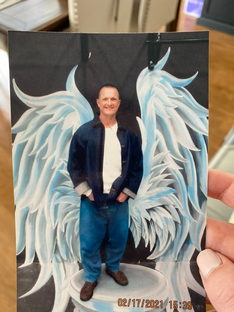 man in prison in front of painted wings