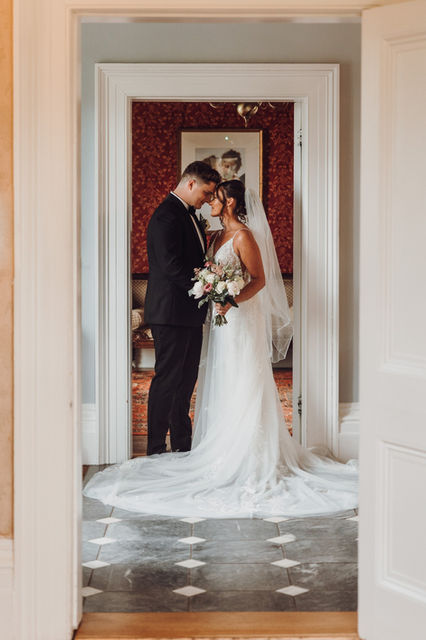 Bride and groom lean into each other in the hallways of the Fennes Wedding Venue