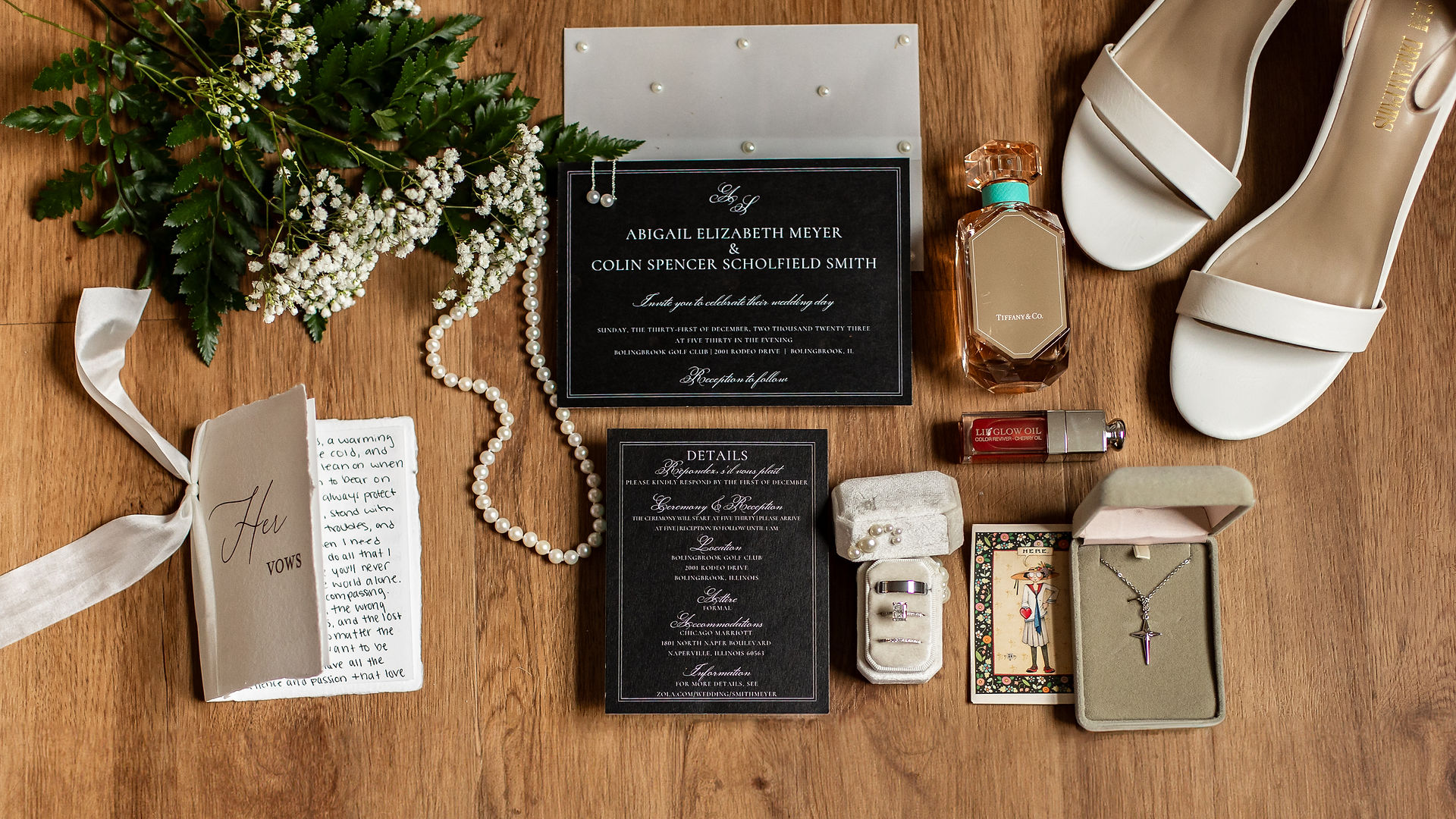 Flat lay of wedding details including perfume, shoes, invites, and jewlery