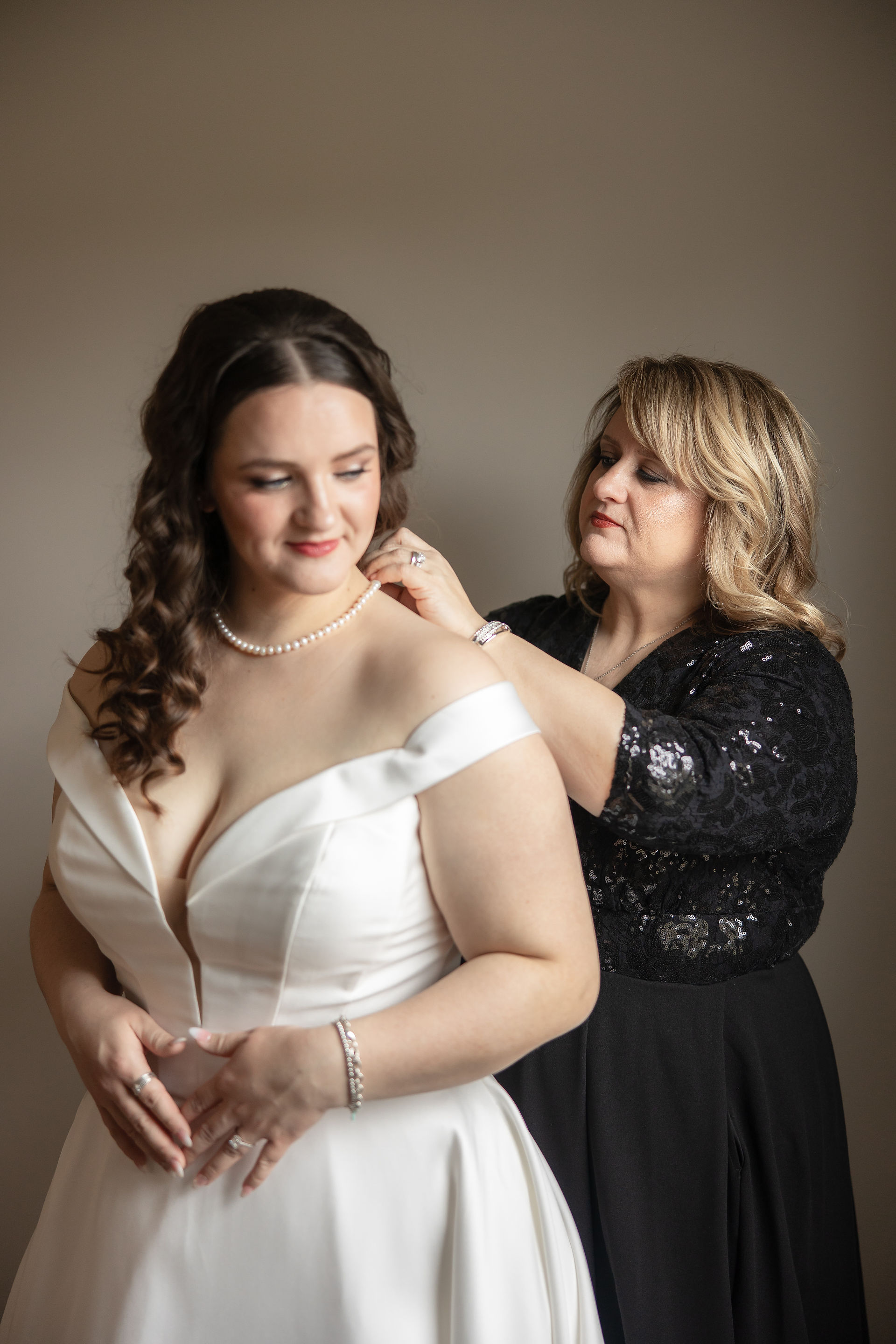 mother of the bride clasping a pearl necklace on her daughter 