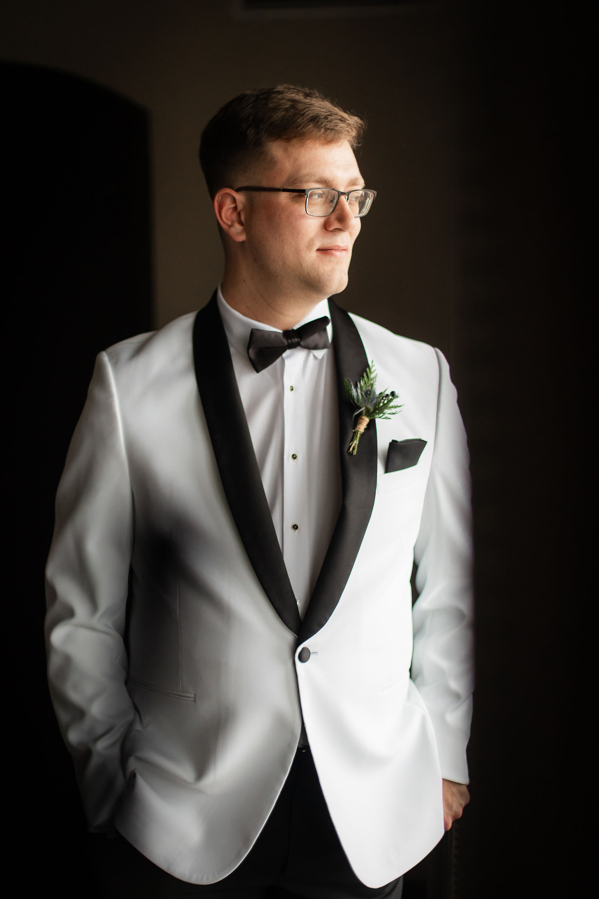moody portrait of groom in white tux