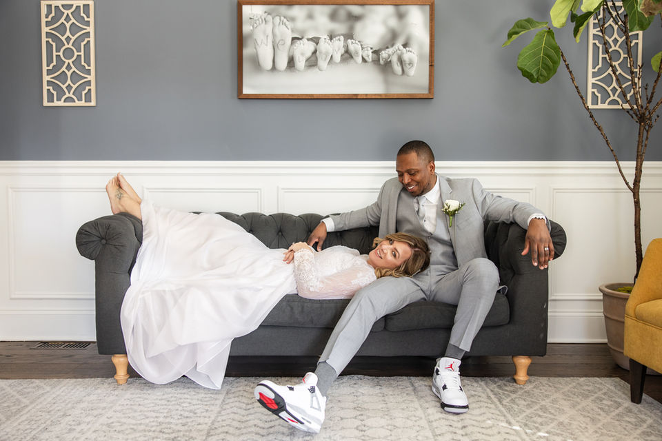 Bride laying on grooms lap at home in their living room 