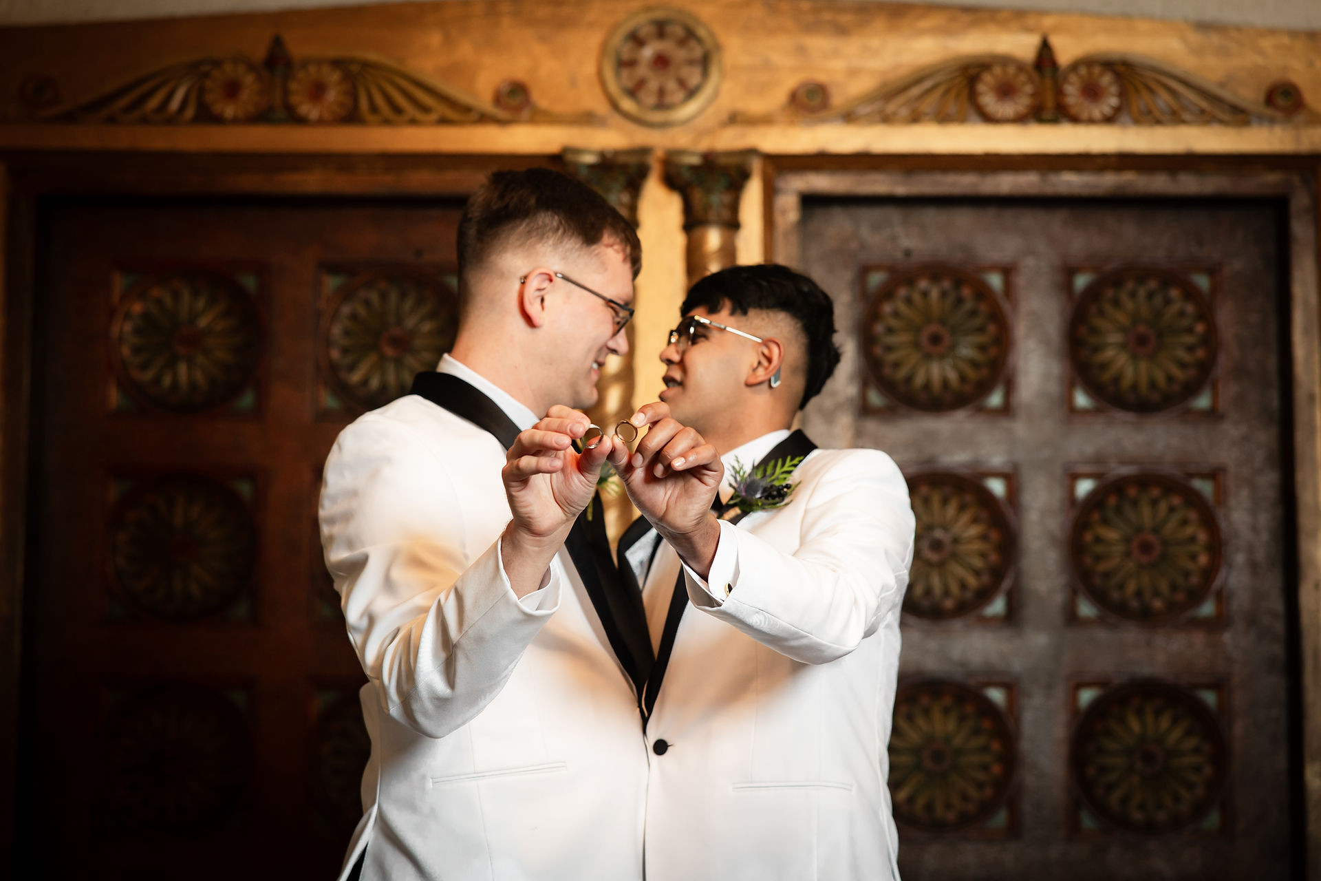 grooms holding up rings with rings in focus