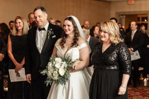 bride with her parents walking down the aisle linking arms