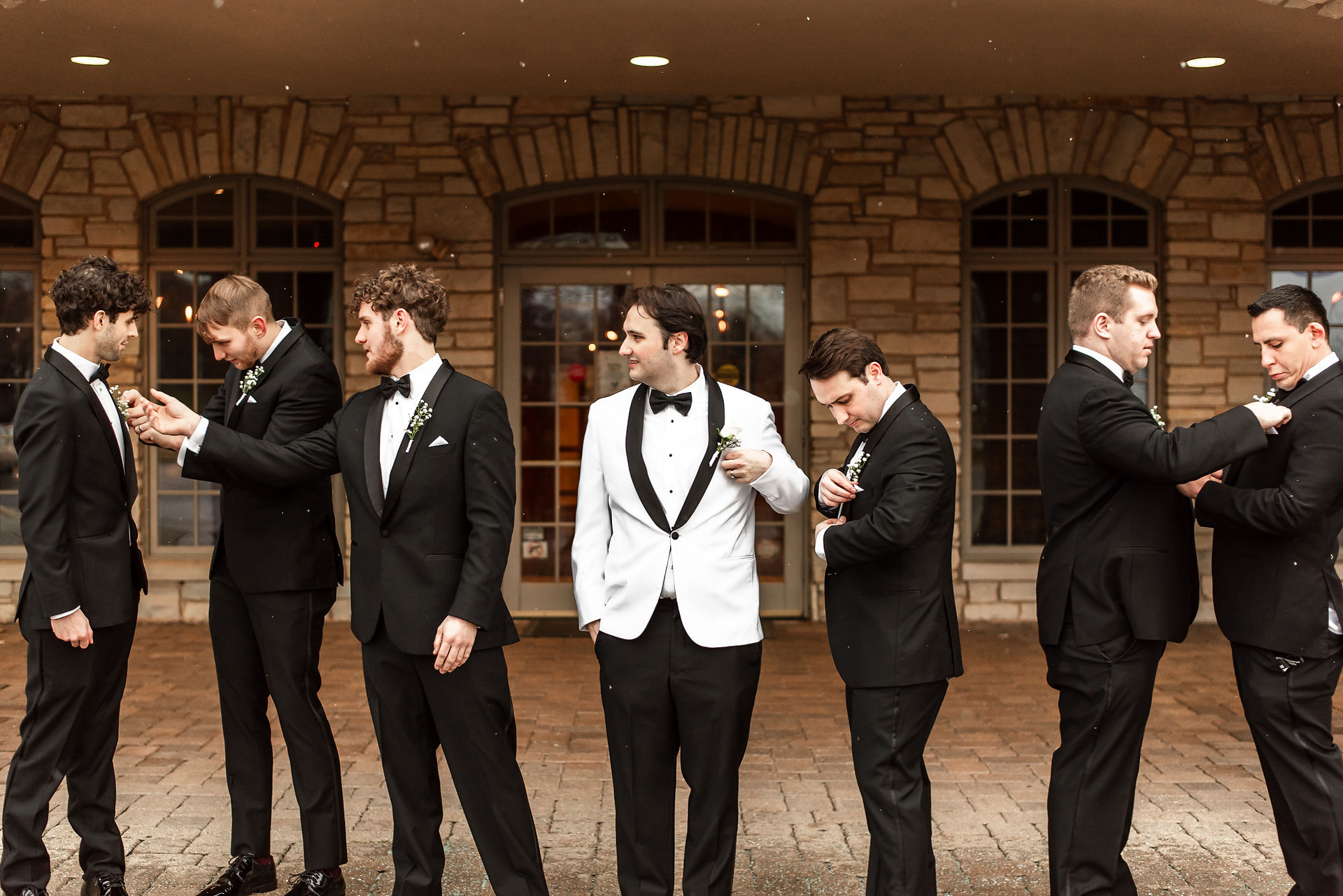groomsmen candidly fixing each others jackets and ties 