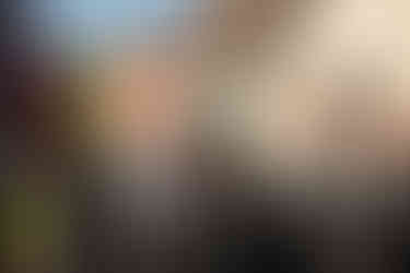 Groom smiling as he is watching is bride walk down the aisle