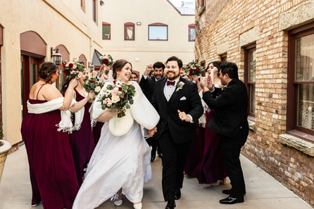 bride and groom running with wedding party hyping them up in a brick industrial setting