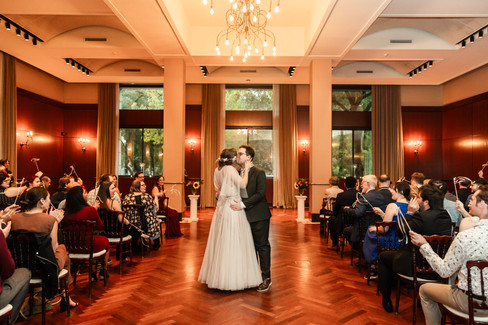 Bride and groom kiss in middle of ceremony aisle with guests cheering