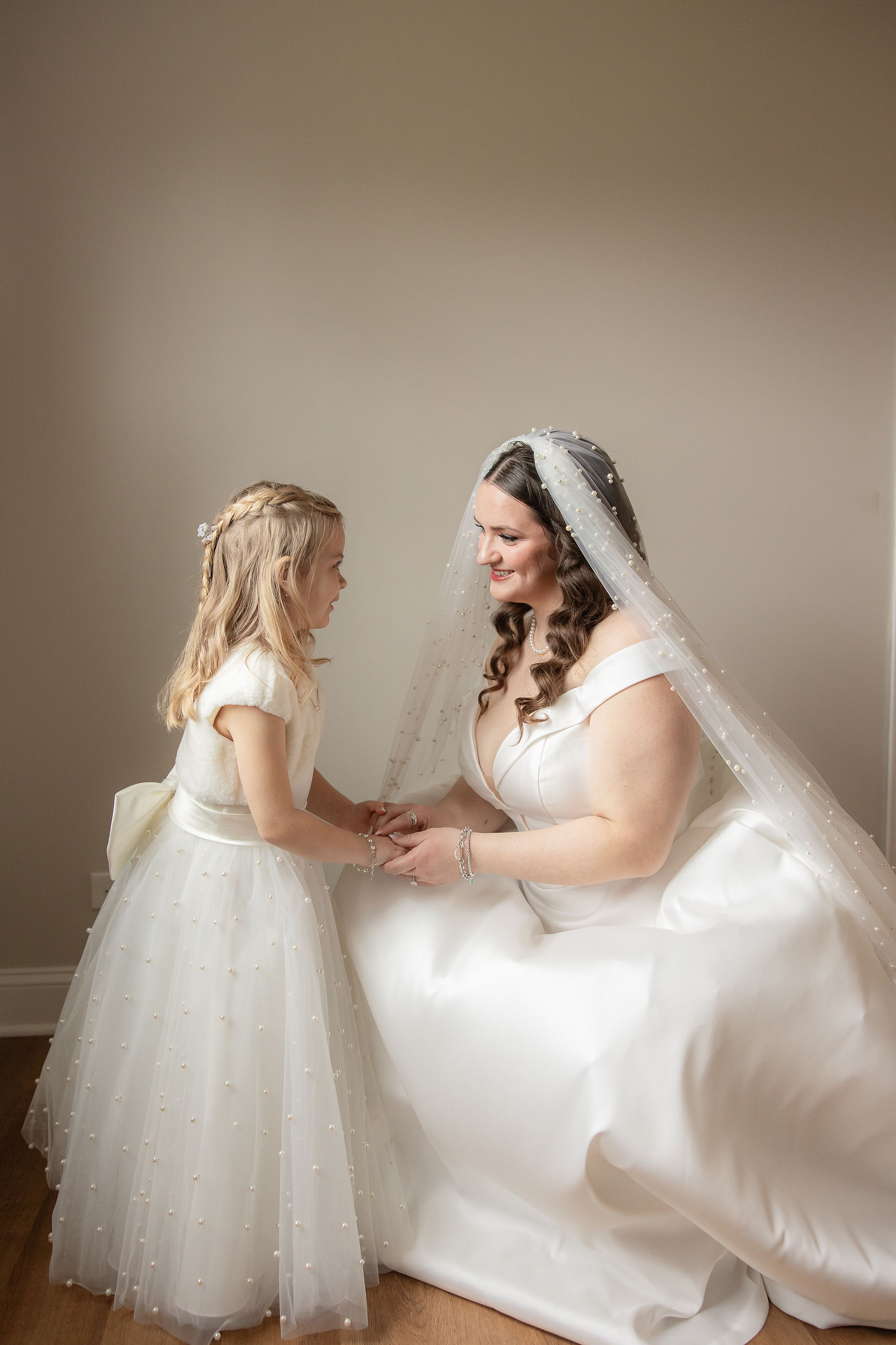 bride and flower girl holding hands and having a cute moment