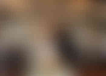 Bride and groom kissing with guests in background after their cake cut