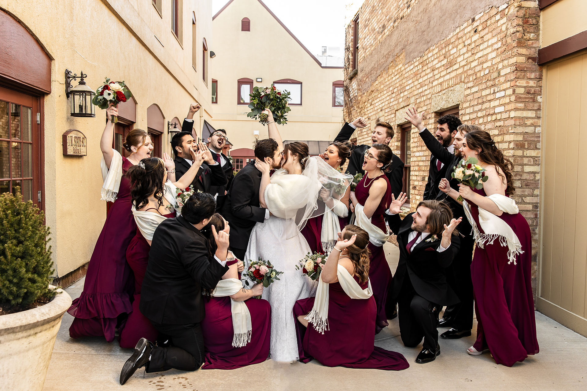 wedding party cheering while bride and groom kiss
