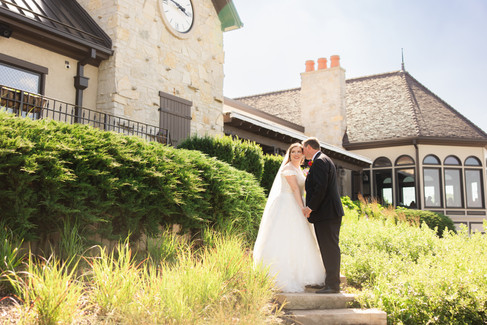 Groom kissing bride on cheek, strongly backlit in front of wedding venue