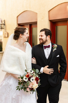 bride and groom walking while looking at each other in front of building with red doors