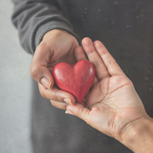 older hand hold a heart together with a younger high school hand both hands are of differe