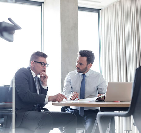 two men in corporate suits talking in an offiice