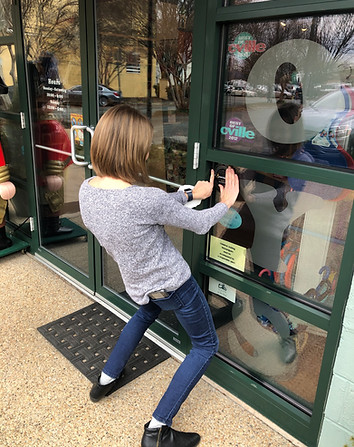Business owner putting their VisitAble sticker up on their storefront.