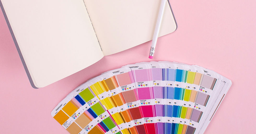notebook on a pink desktop with an opened Pantone book
