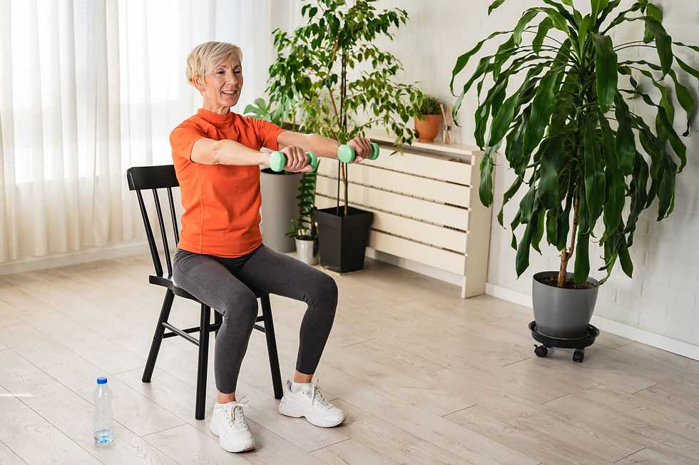 Older woman exercising at home while seated on a chair, holding light dumbbells with arms extended forward, demonstrating a safe low impact strength movement.