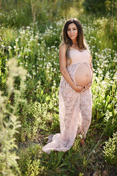 Mother-to-be in a blush lace open-front gown holding her belly in a wildflower field, captured by a Sacramento maternity photographer