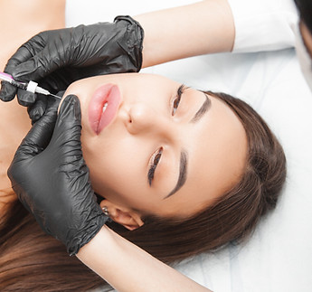 A cosmetologist makes lipolytic injections to burn fat on a woman's chin against a double 