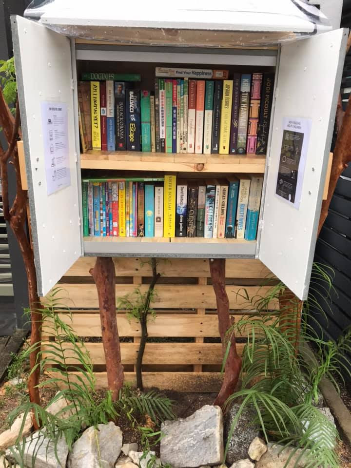 A makeshift outdoor shelf with books outside a home.