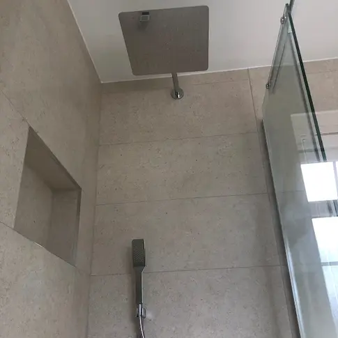 Modern shower head in a clean bathroom with glass door.