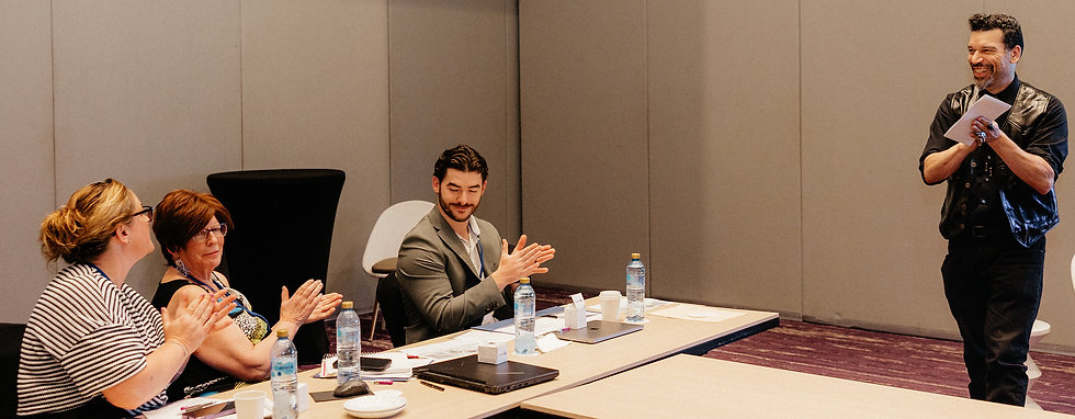 S. Scott Mason smiles while holding his notes as three participants applaud during a leadership workshop.