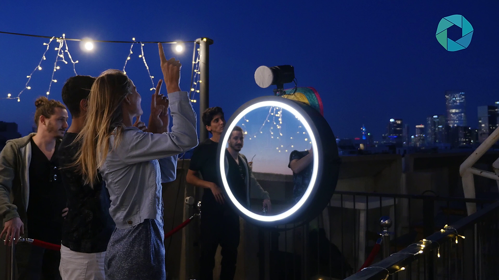 People posing at an interactive mirror photo booth at night.