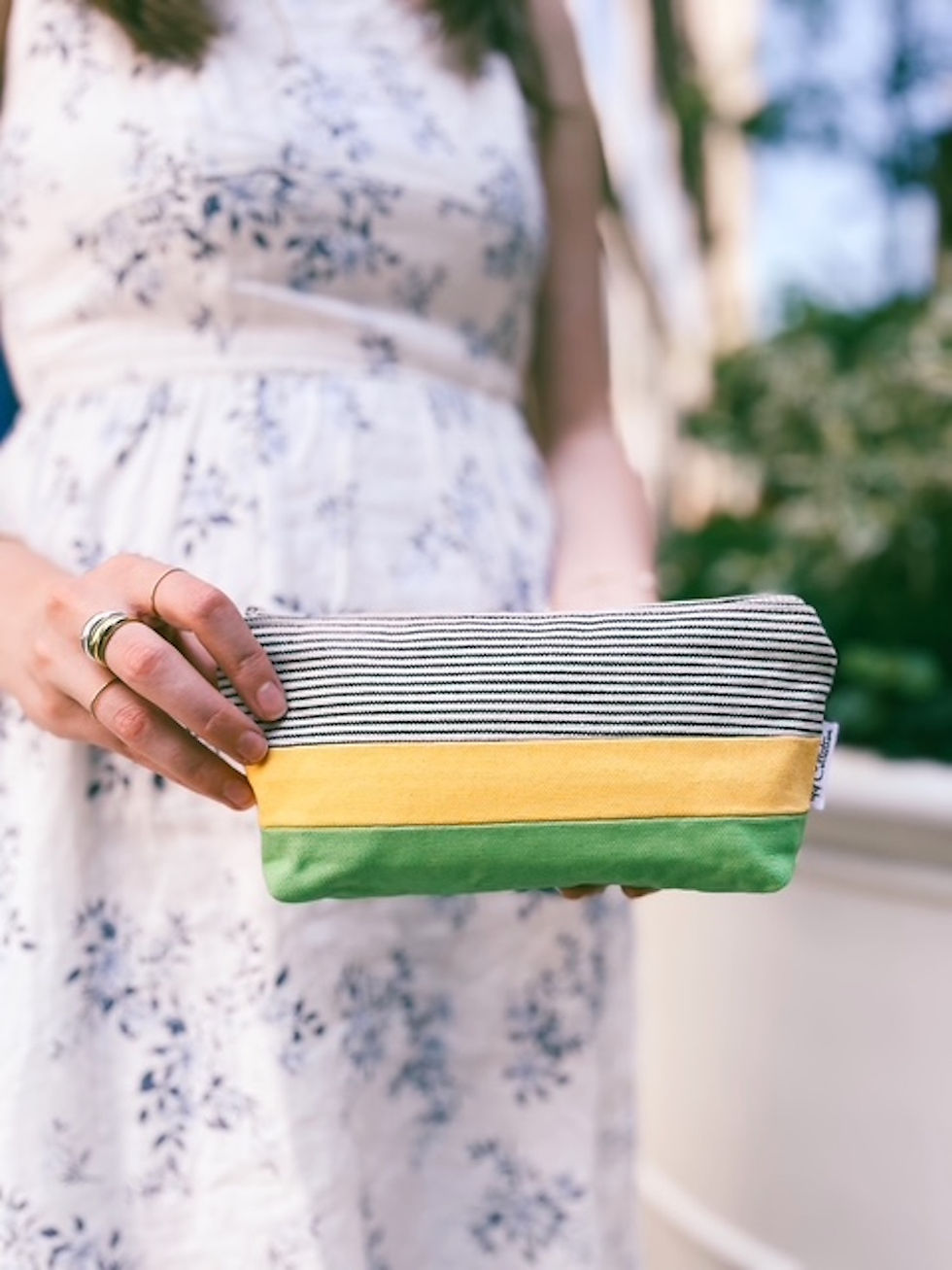 woman holding yellow and green canvas cosmetic pouch