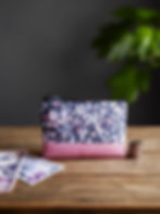 Thumbnail: leaf and berry gray print leather change purse on a wooden table with cash and coins