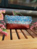 strawberry thief teal cute toiletry bag for women outdoors on a wooden bench surrounded with pink flowers