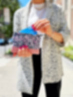 Thumbnail: pink leather accented gray floral coin purse held with credit card shown by woman outdoors