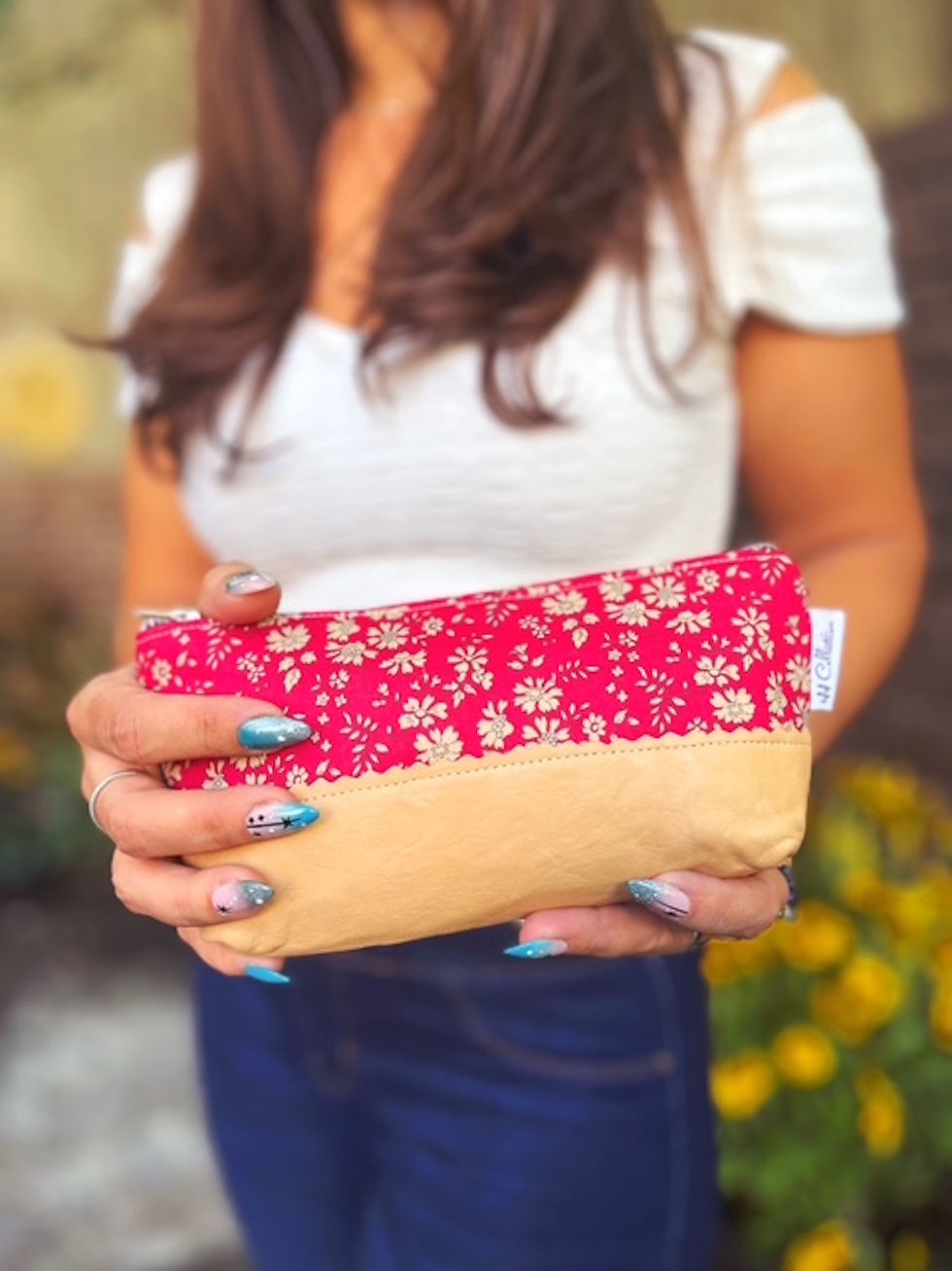 woman holding red floral zipper makeup bag with beige leather accent