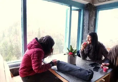Two YouFinder participants sharing a quiet conversation and writing beside a sunlit window.